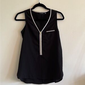Black sleeveless blouse with white trim and gold zipper